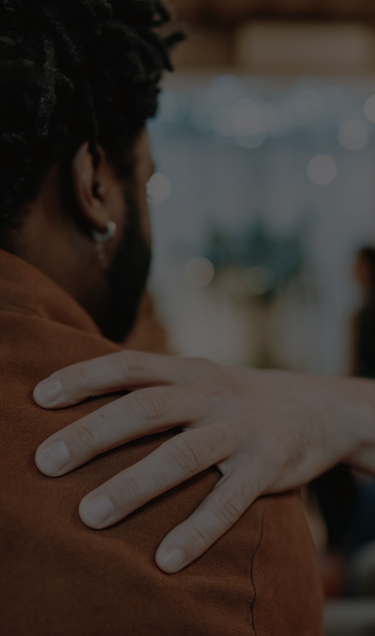 A man supports another man in a peer support group for addiction recovery.