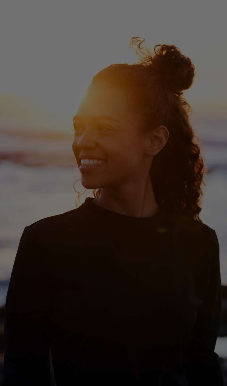 A woman visits the beach at sunrise after completing addiction treatment.