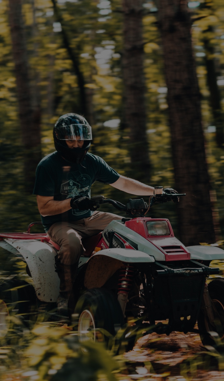 A client cruises through an ATV trail in the forest.