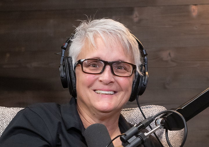 Dr. Tami Romano talks into a microphone on The Circle of M podcast.