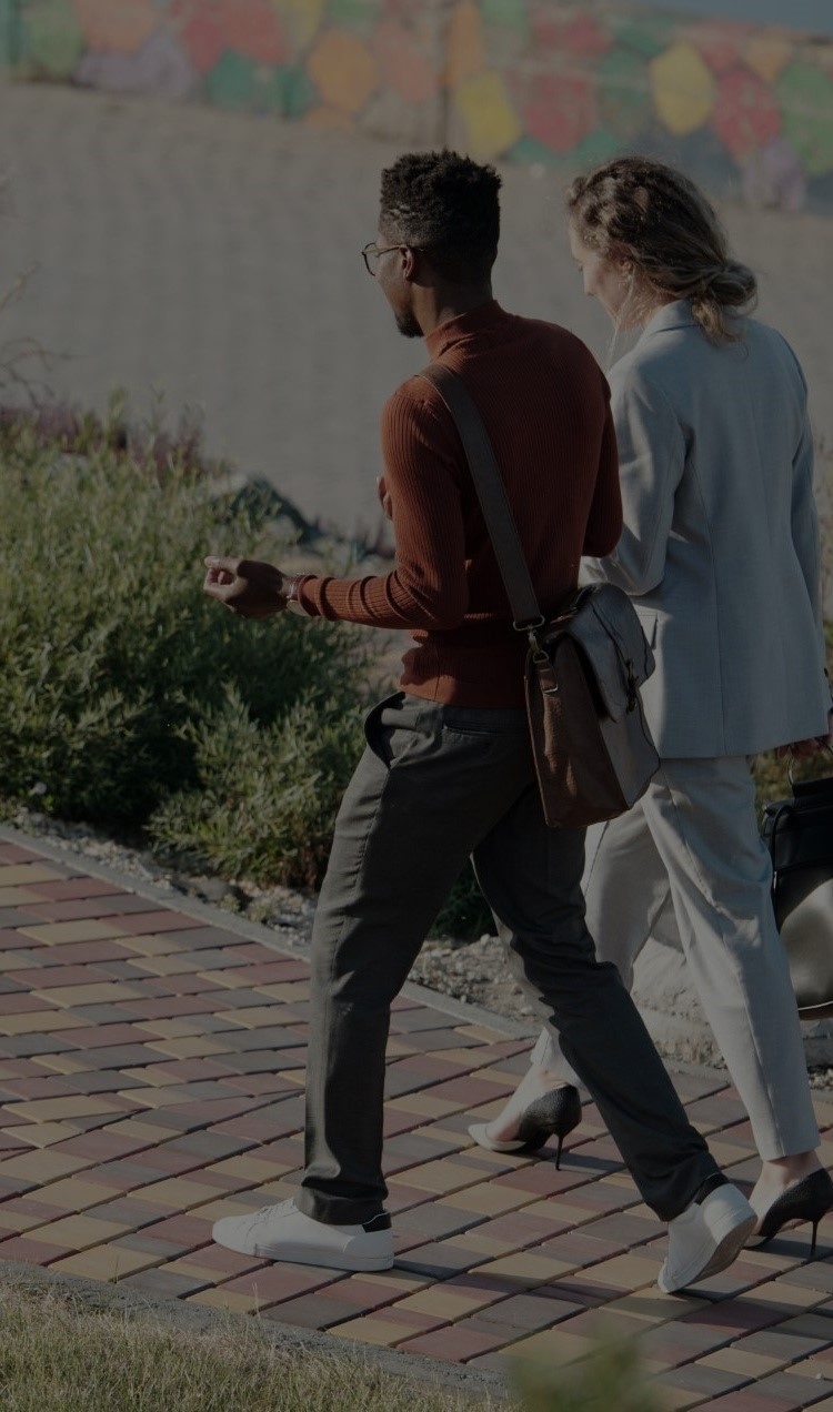 A man and woman walking on sidewalk and talking