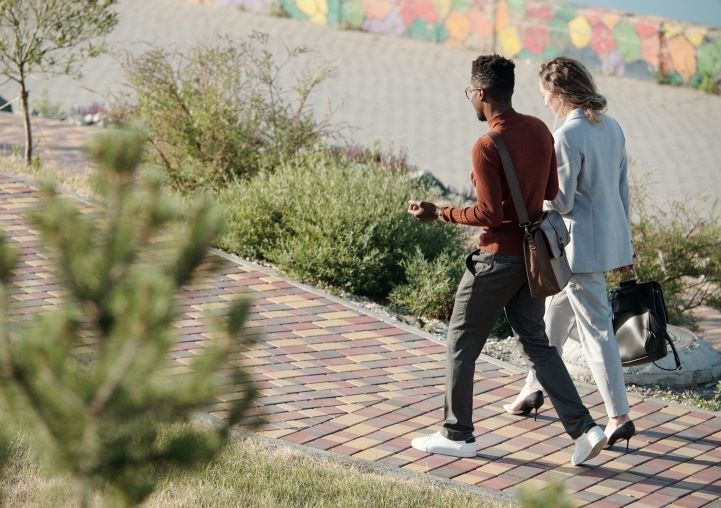 A man and woman walking on sidewalk and talking
