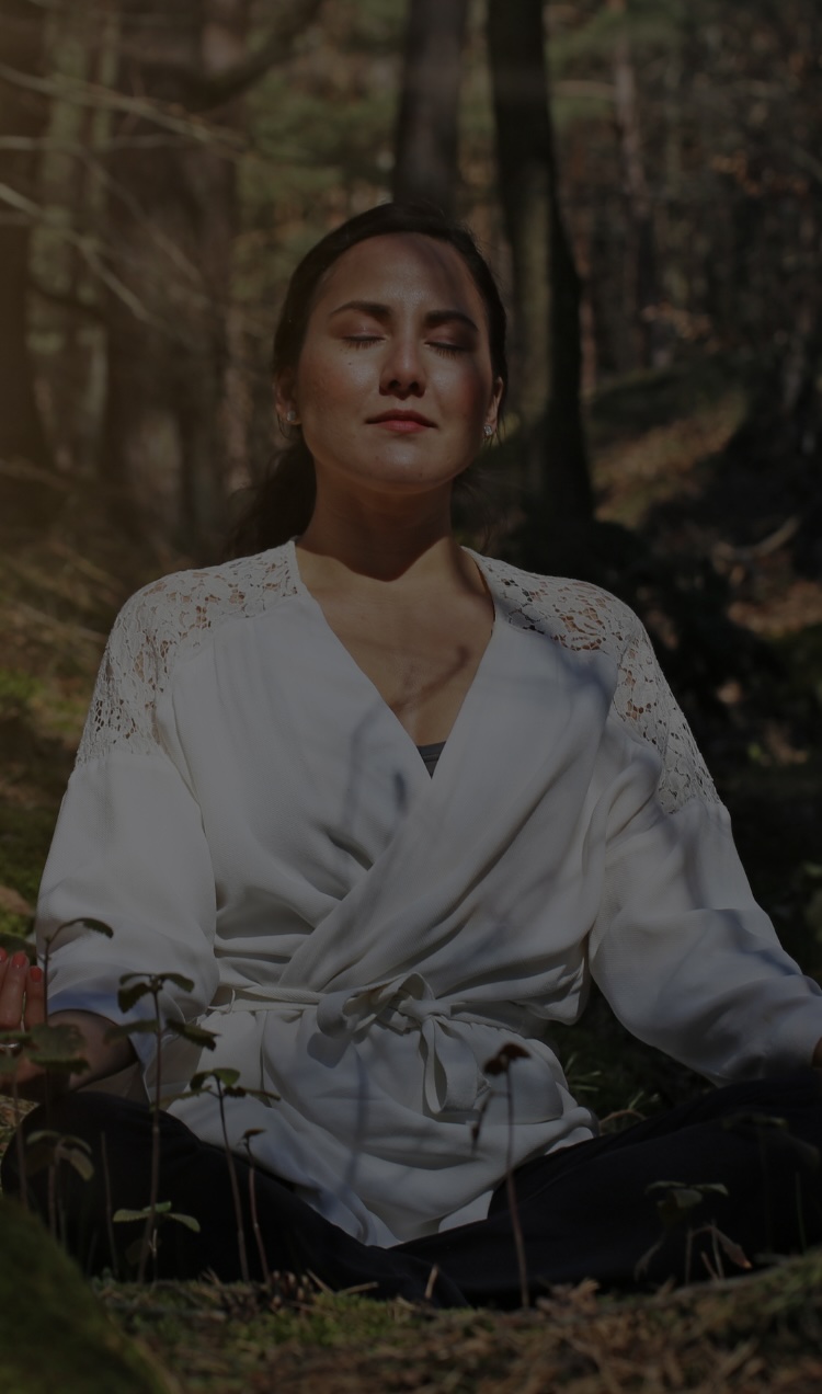 A woman meditates in the forest.