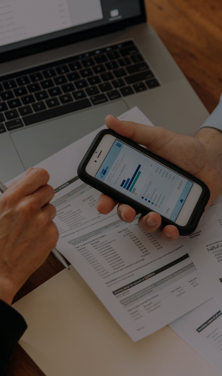 A family reviews finances with a mobile app, paper records, and an open laptop.