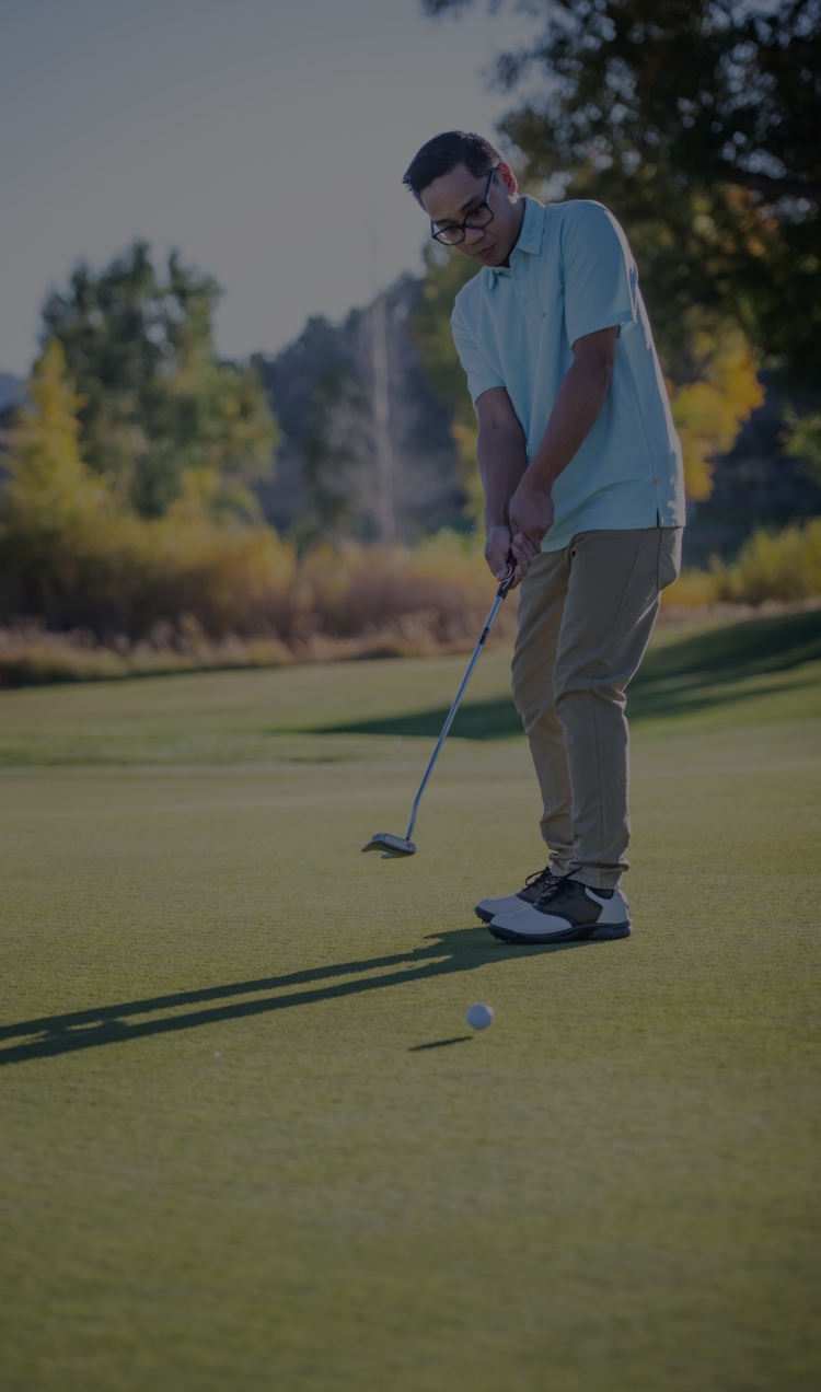A client takes a final shot on the putting green.