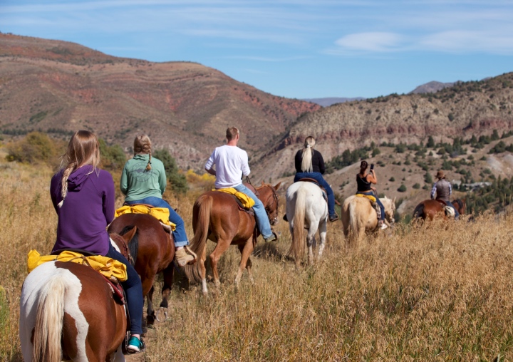 A train of horses with riders navigating the trails in Colorado.