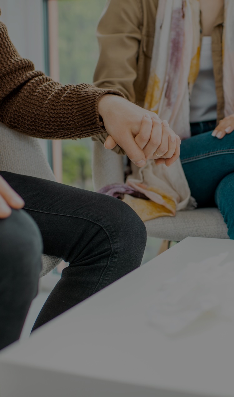 A couple holds hands during a sit down conversation ahead of a couples therapy session.