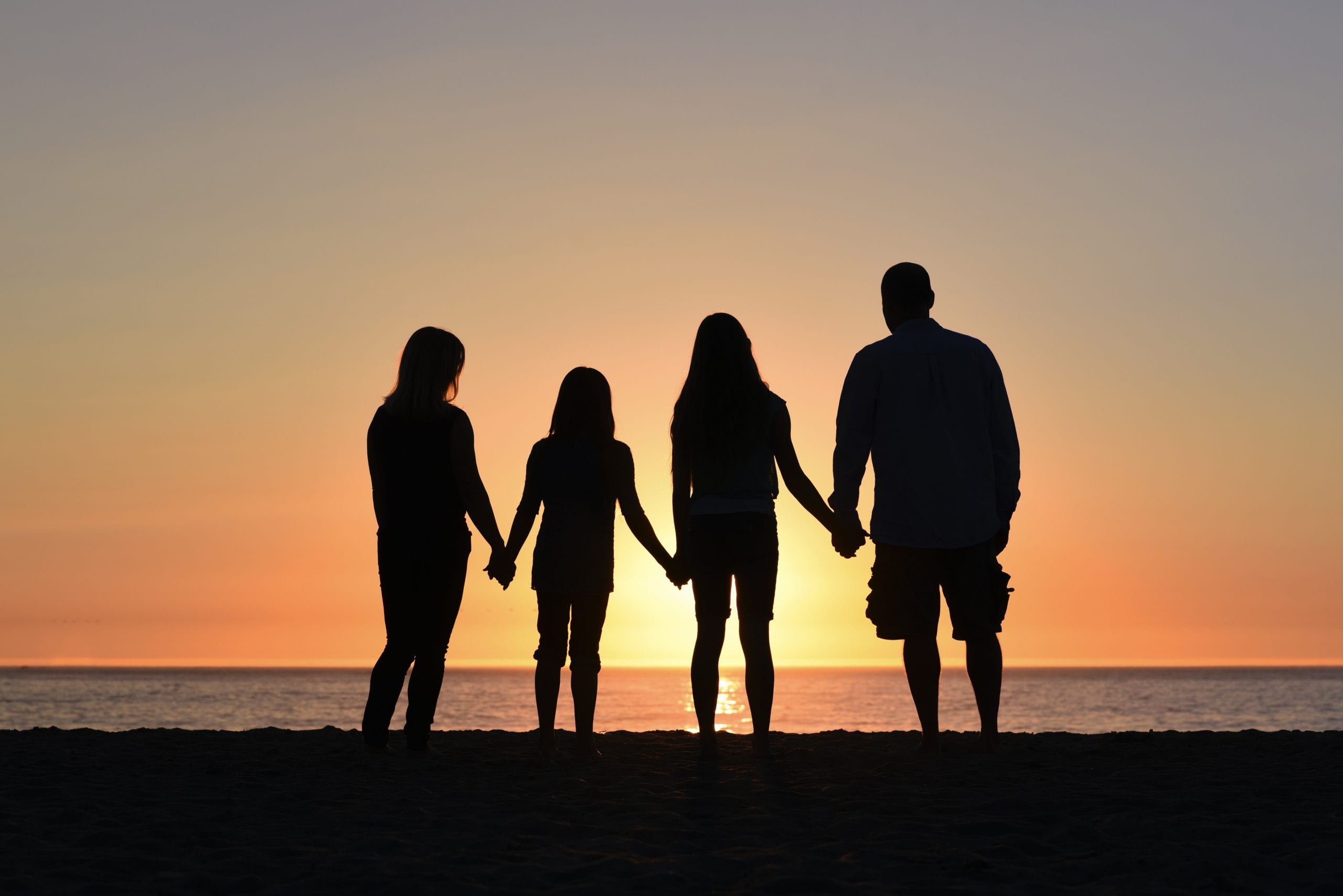 family silhouette holding hands at sunset