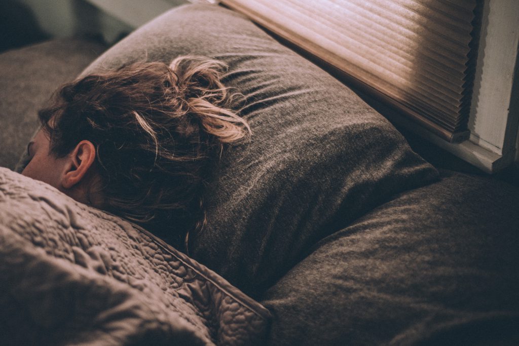 A woman curled in bed beneath the blankets.