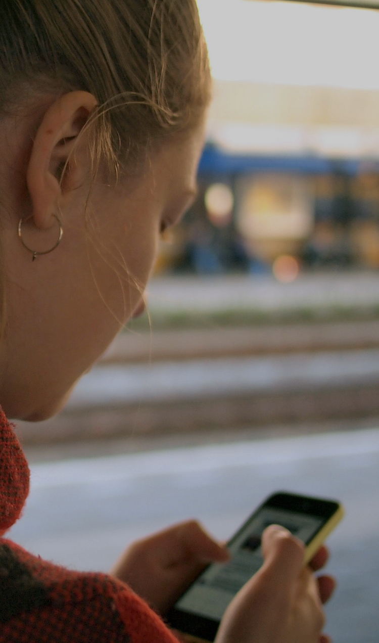 A woman checks her email on her phone while waiting for the train.