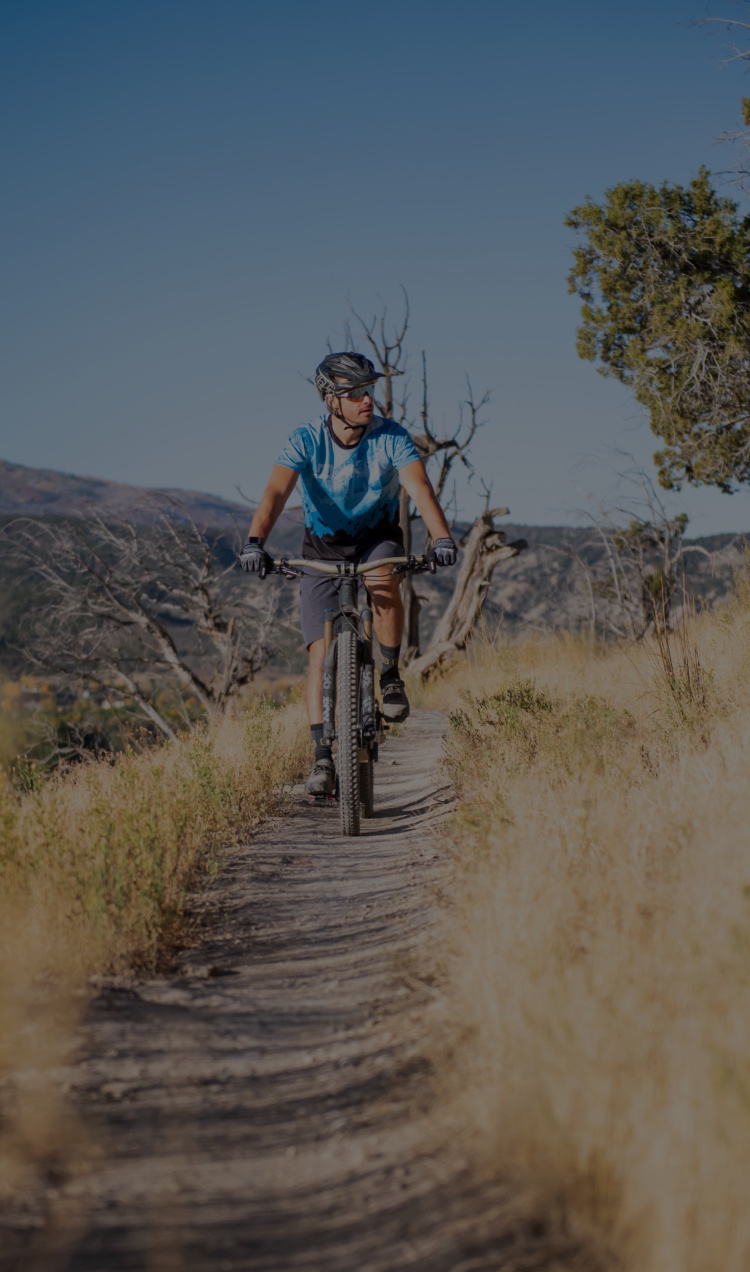A man on a mountain bike follows the trail through the mountains.