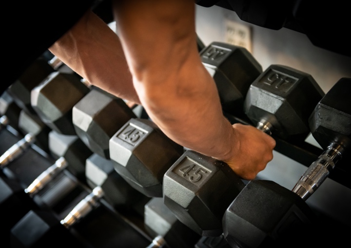 A client grabs free weights from the rack at the gym.