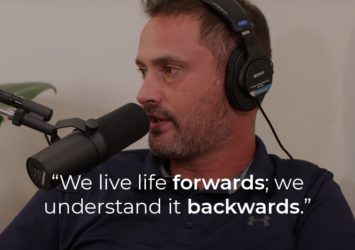 Andy Silvagni speaking into a podcast microphone with a text overlay: We live life forwards; we understand it backwards.