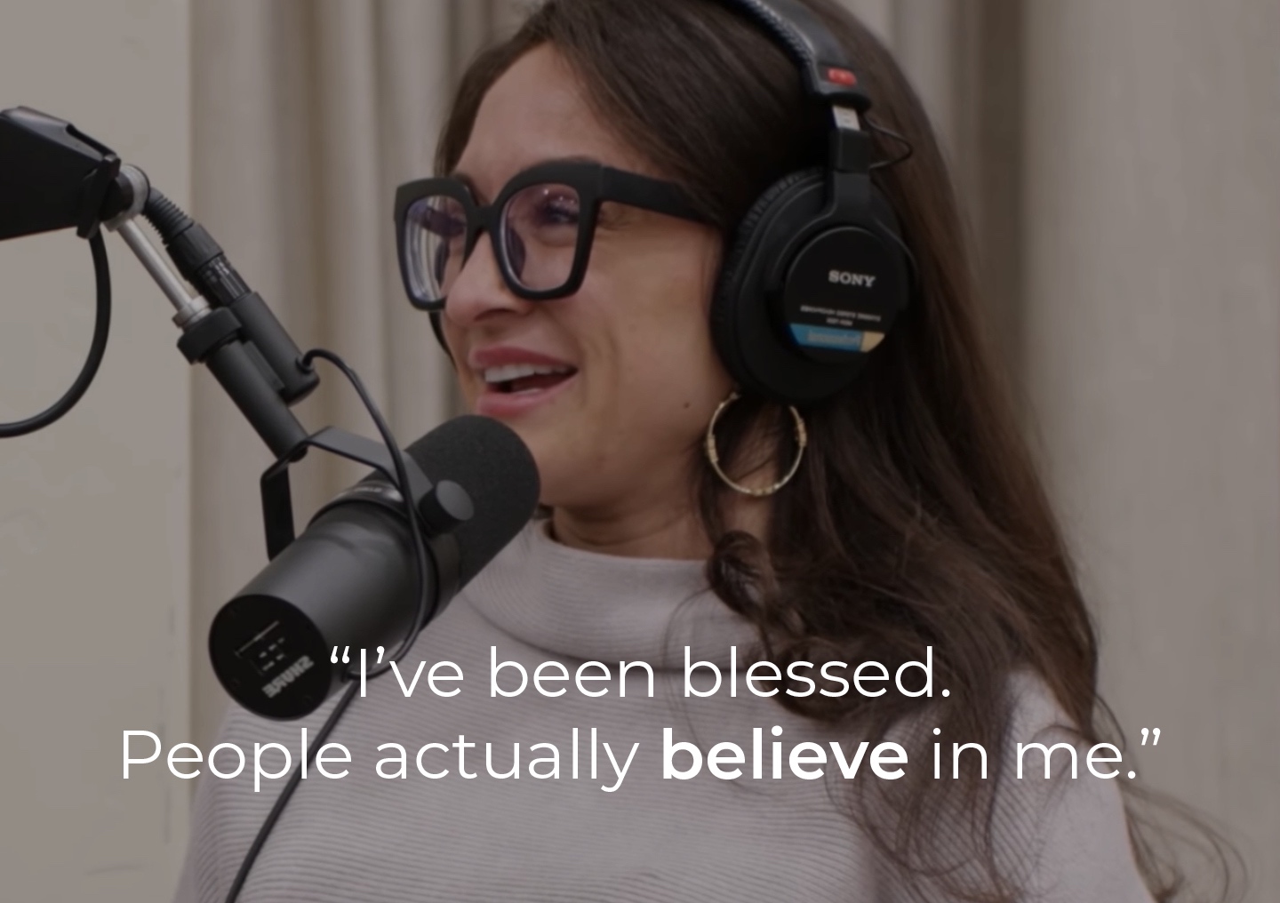 Ashley speaking into a podcast microphone with a text overlay: 