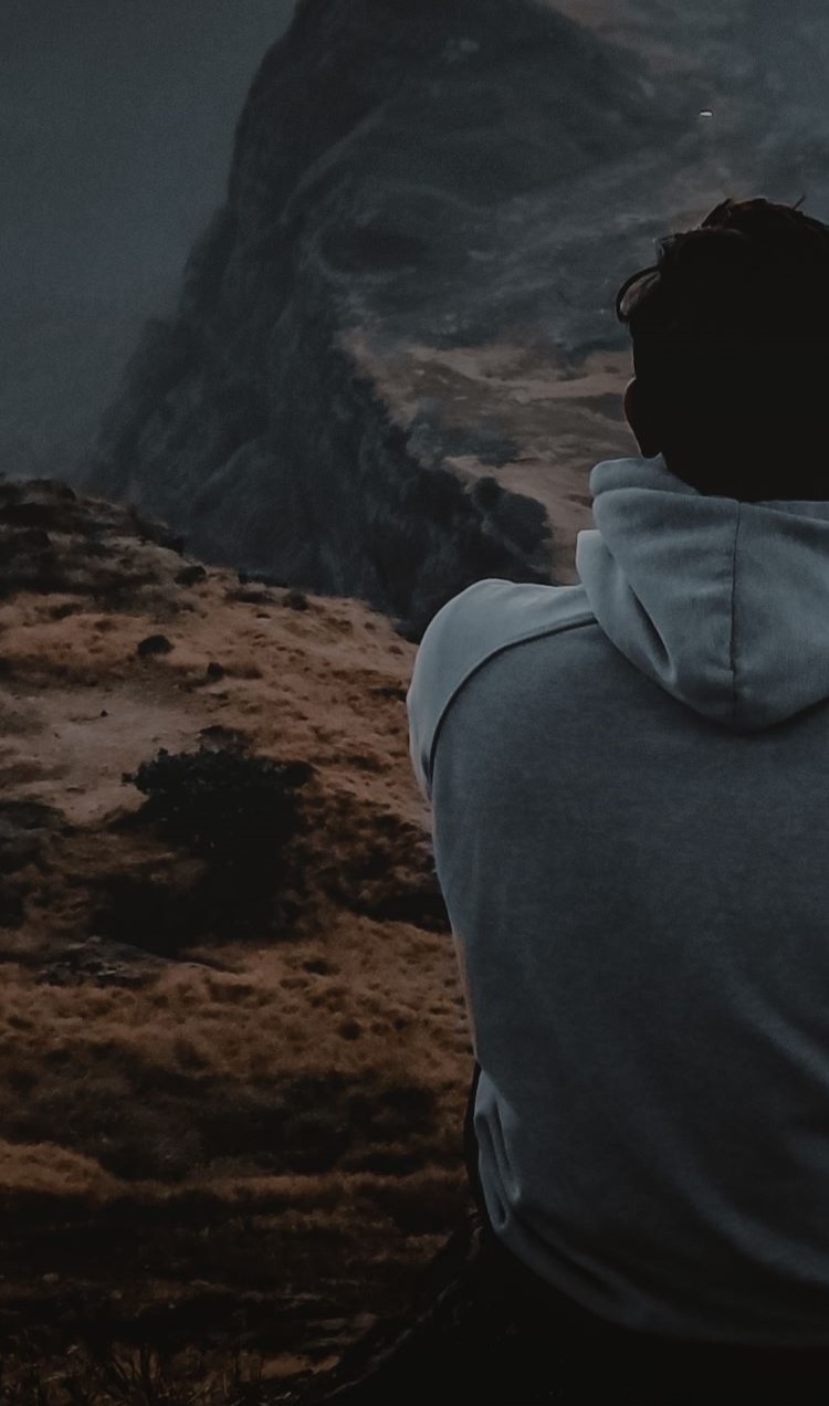 Man Sitting on Cliff Watching Sunset