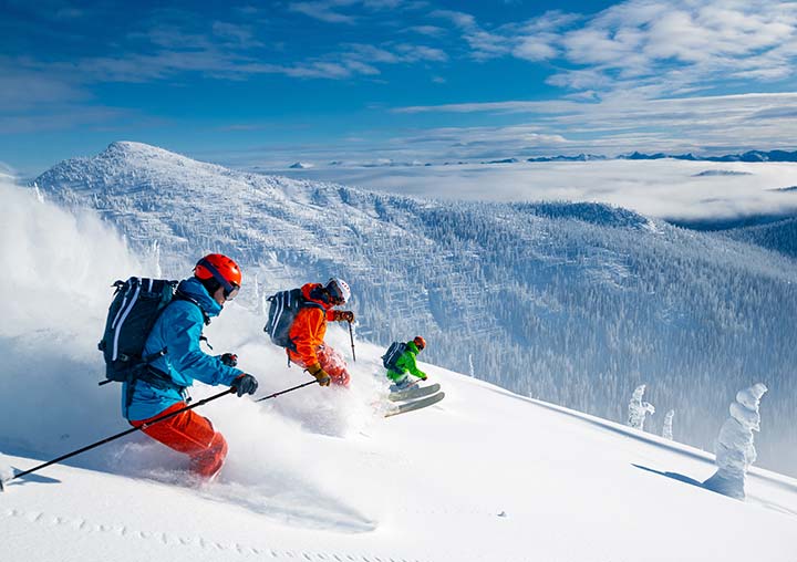 Three people skiing and snowboarding down a mountain