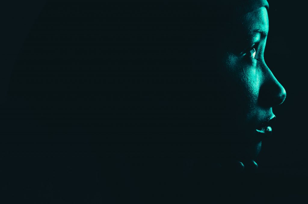 Profile of a woman looking to the right, lit by a green neon light.