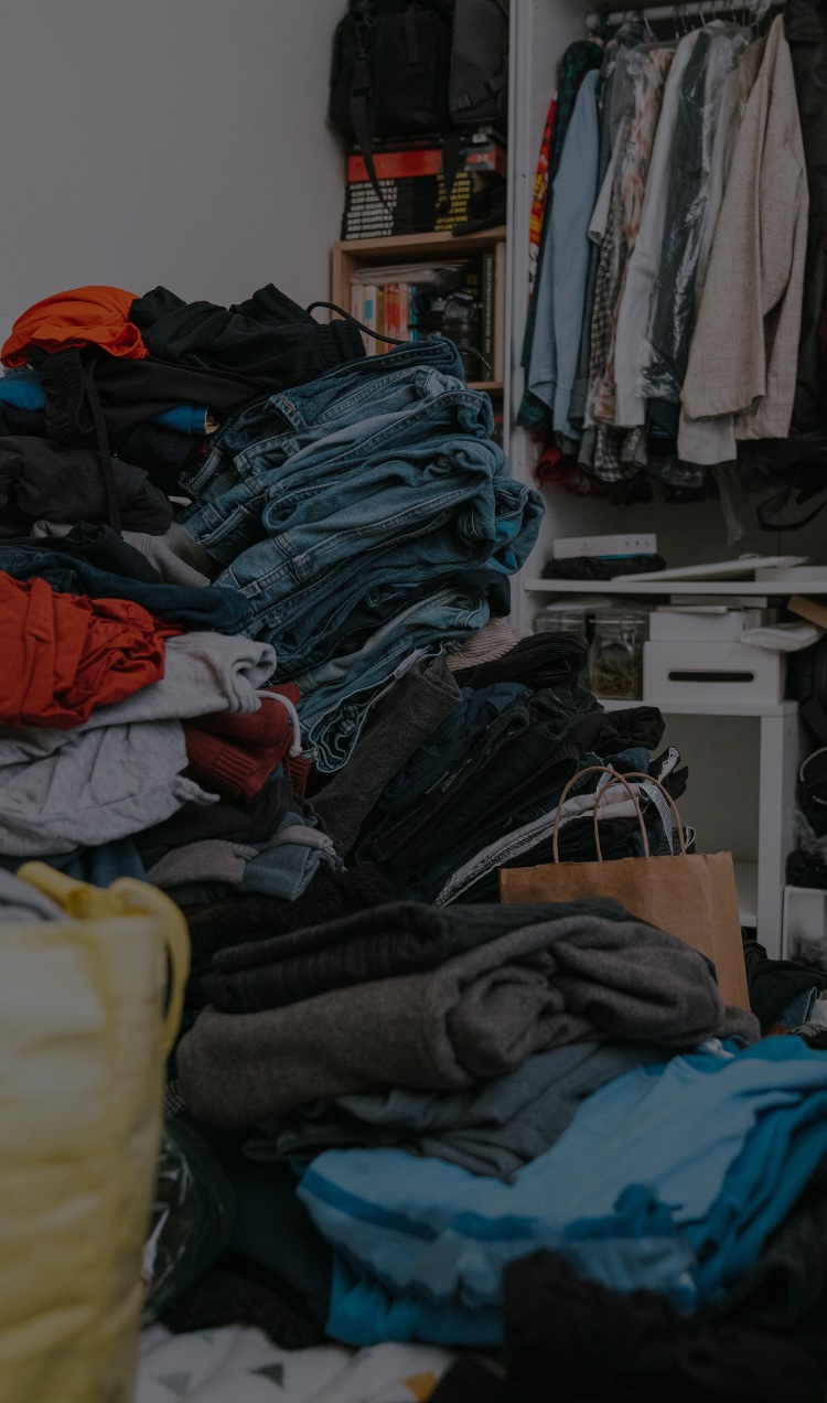 A cluttered closet with overflowing clothes.