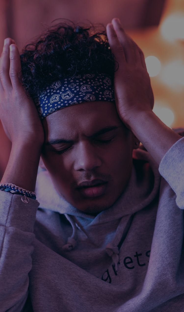 A man holds his head with his eyes closed after a relapse.