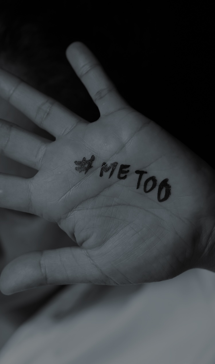Someone holds their hand out with fingers spread and #metoo written in marker on their palm.
