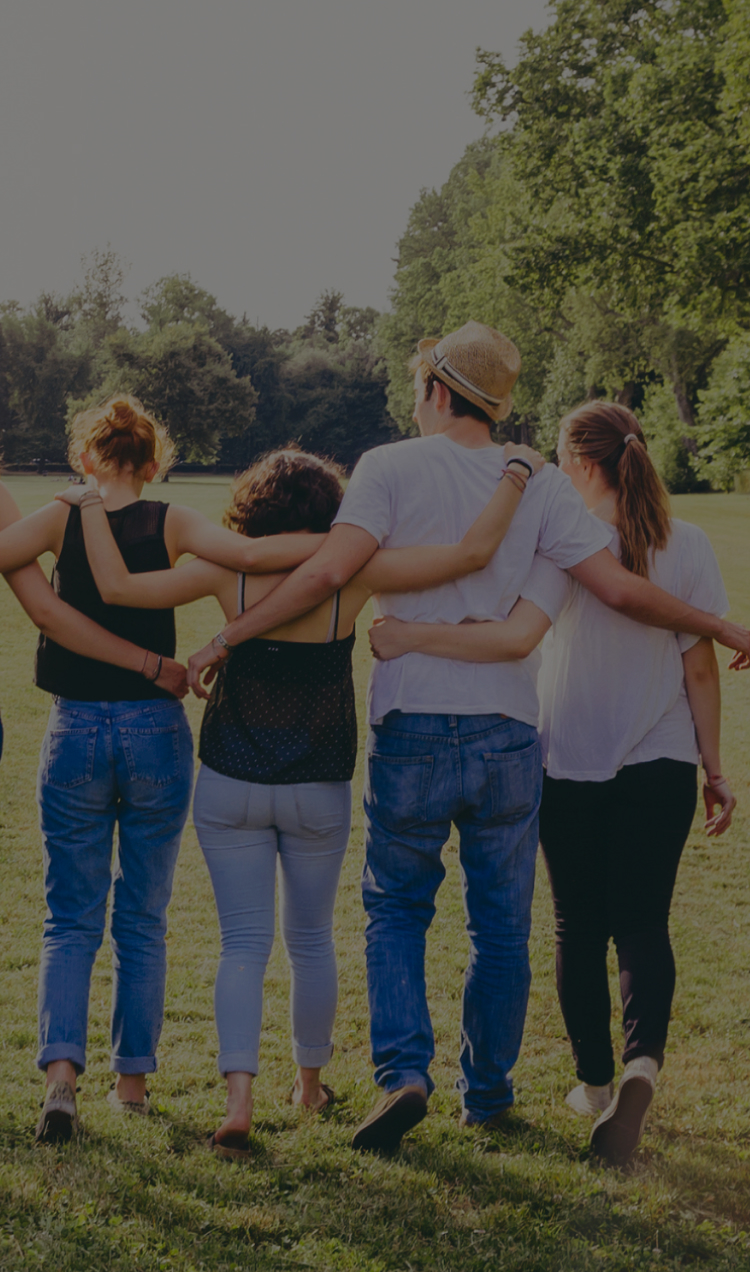 A group of four friends walking together with their arms wrapped behind each other.