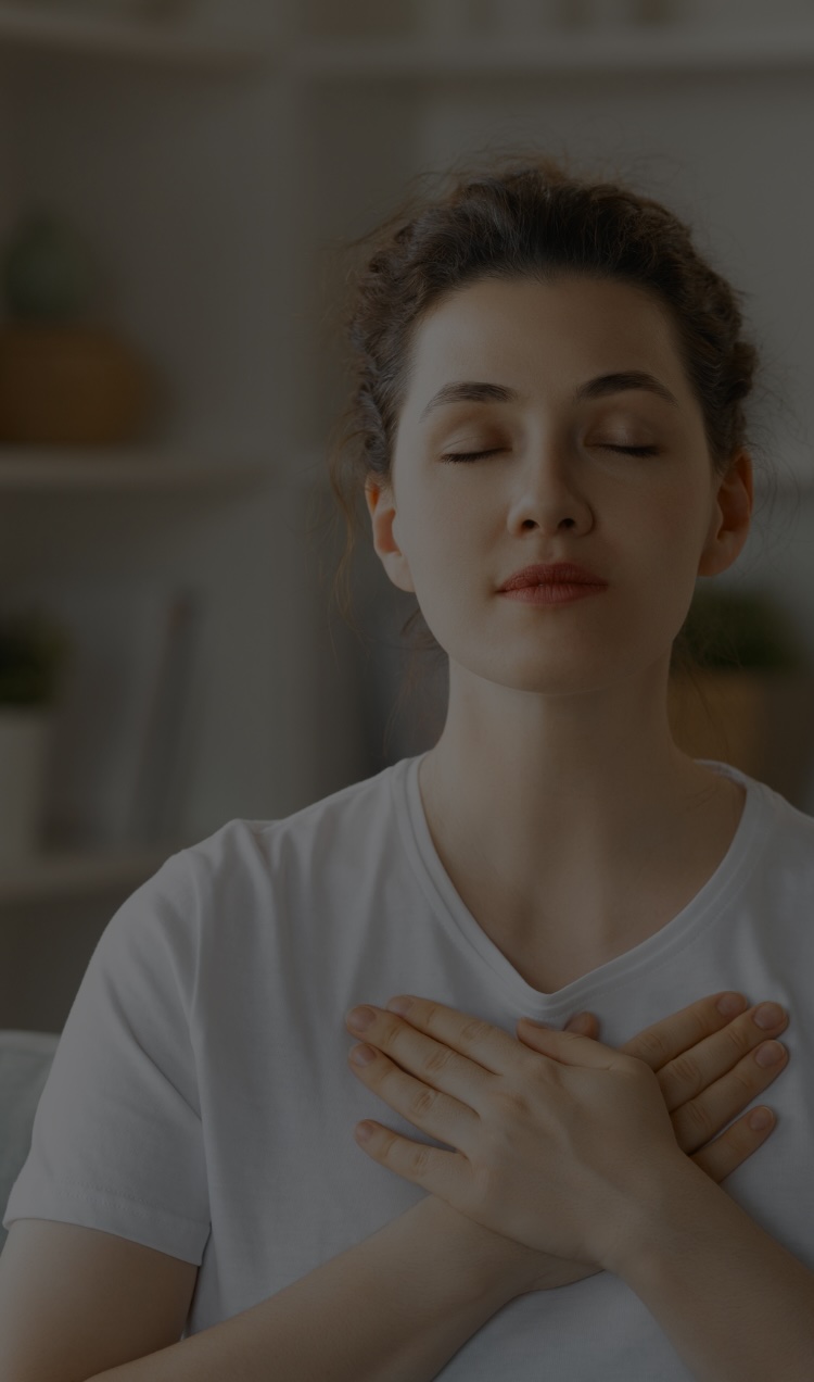 A woman holds her chest with her eyes closed during a somatic experiencing session.