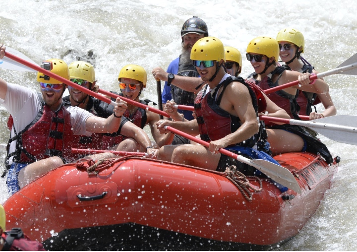 A raft full of people careens down the rapids.