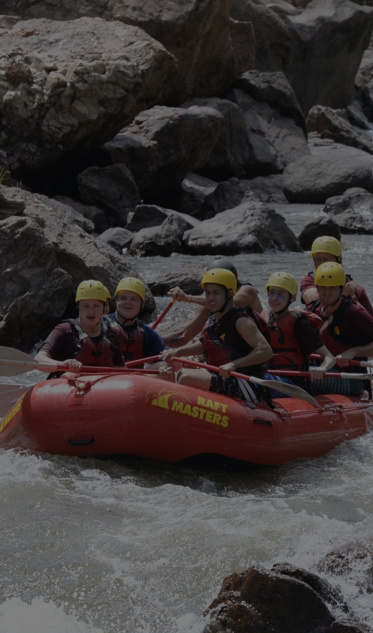 A raft full of people careens down the rapids.