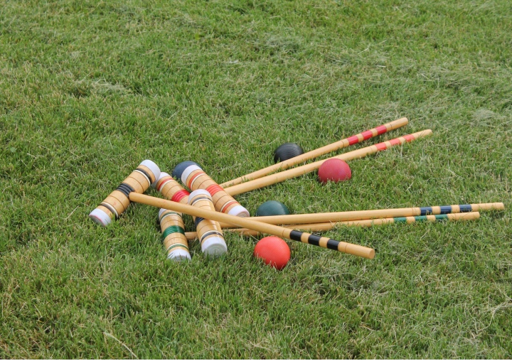 A set of croquet mallets and balls on the grass.