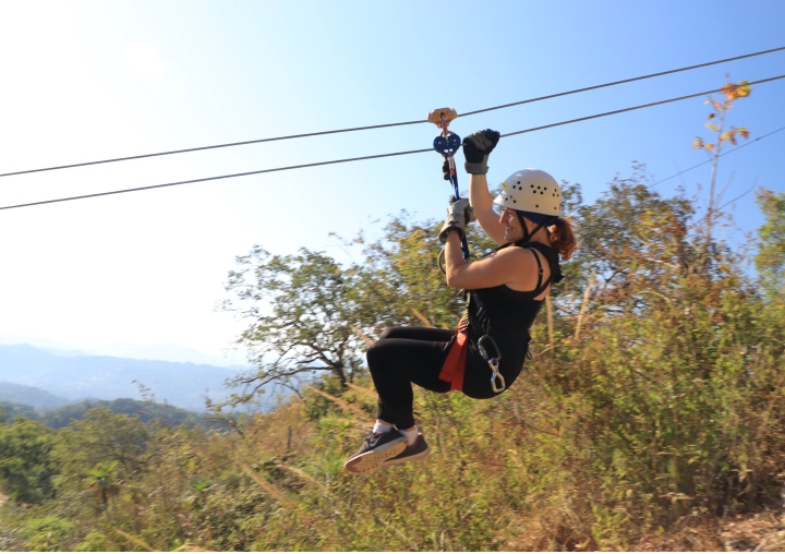 A woman ziplining through the trees.
