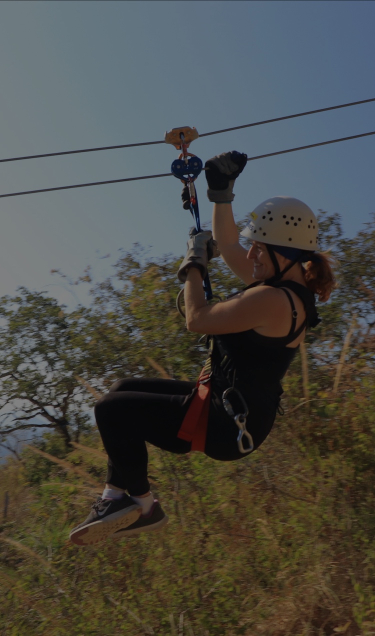 A woman ziplining through the trees.
