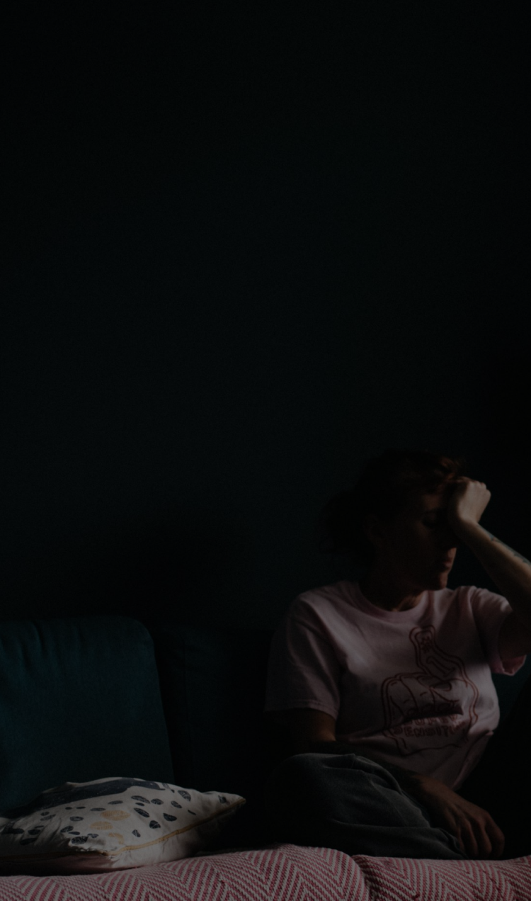 A man sitting in a dark room with his head in his hands.