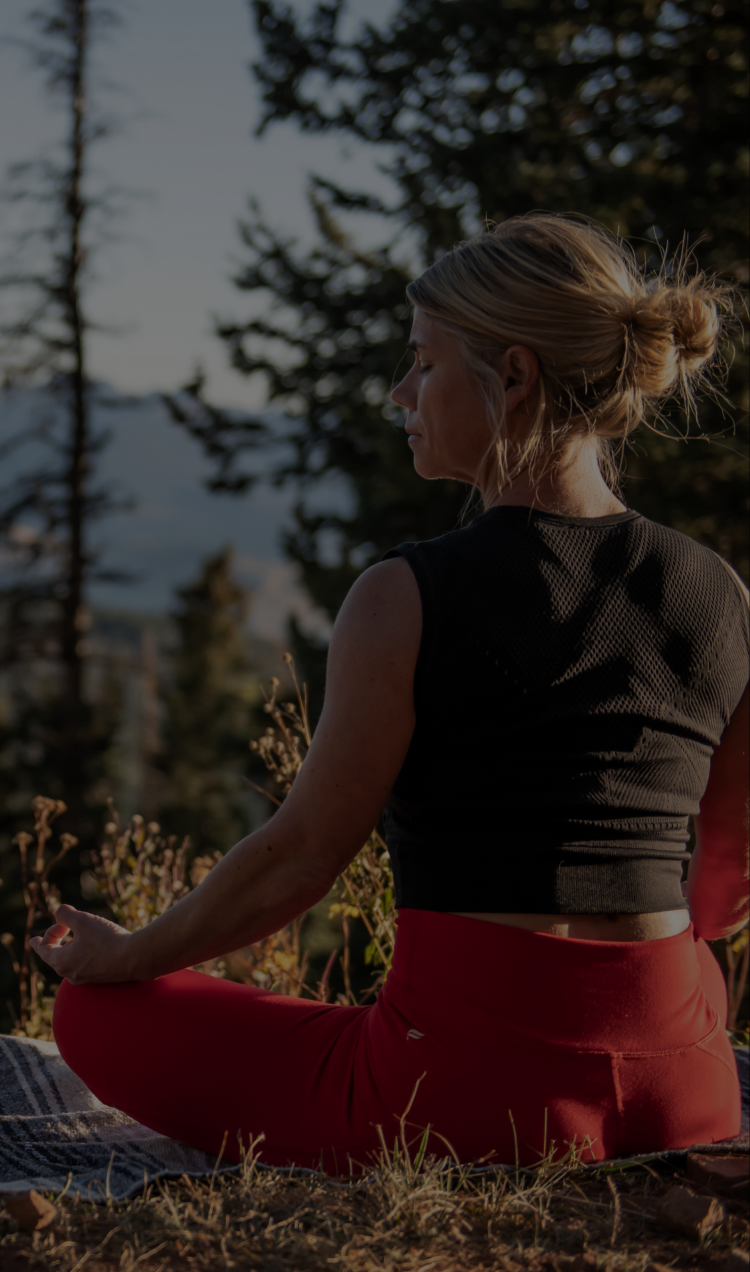 A client practices meditation outside of All Points North Lodge overlooking the Colorado mountains.
