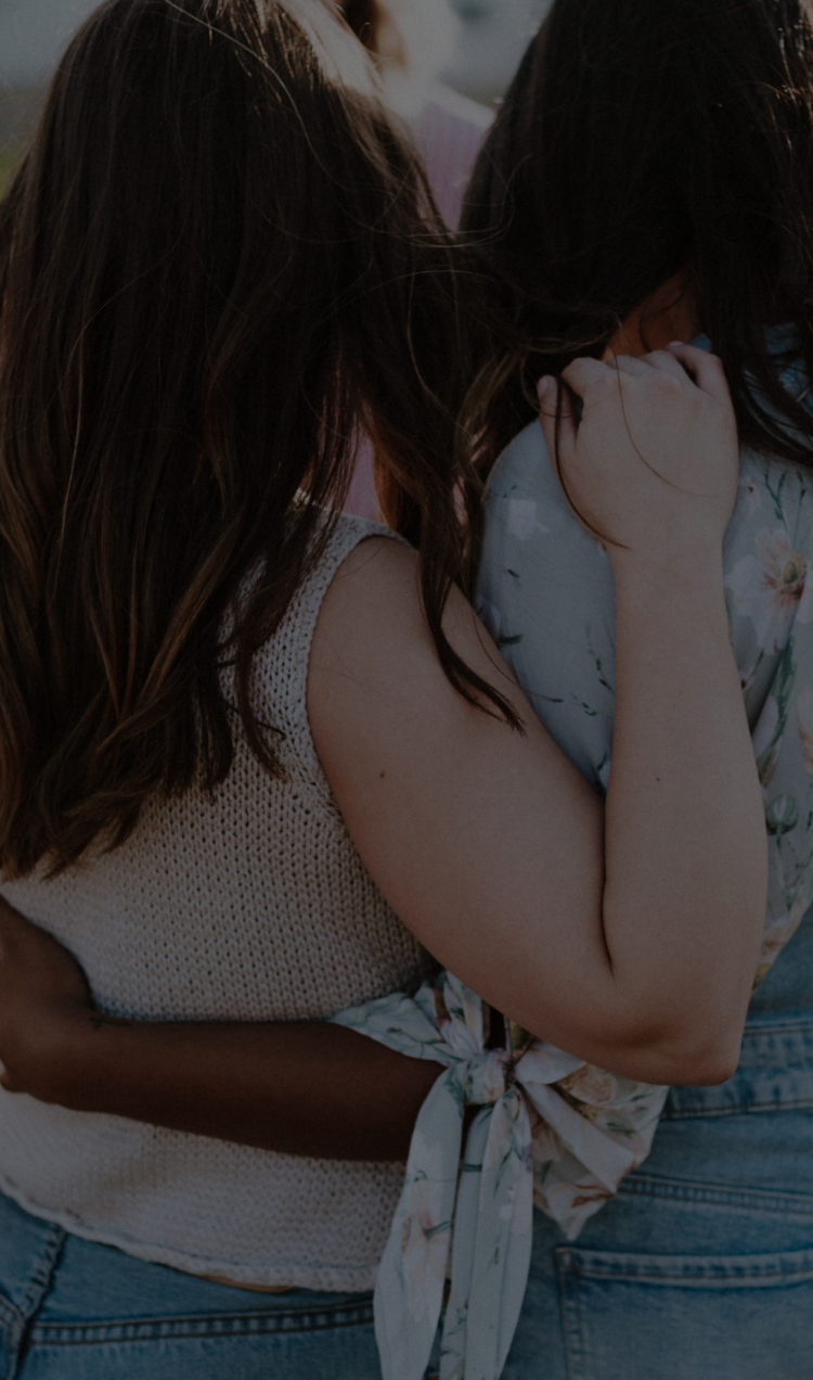 Two women holding each other in a field of flowers.
