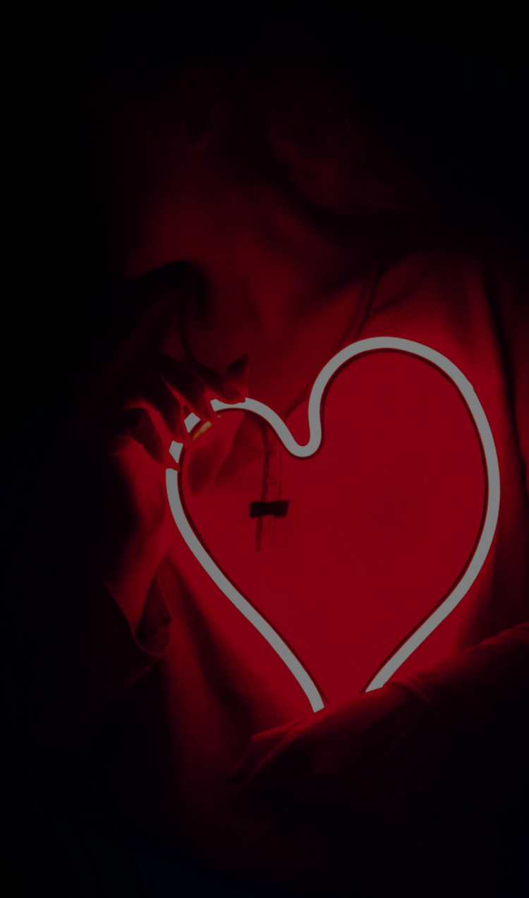 A person holding a red neon heart light.