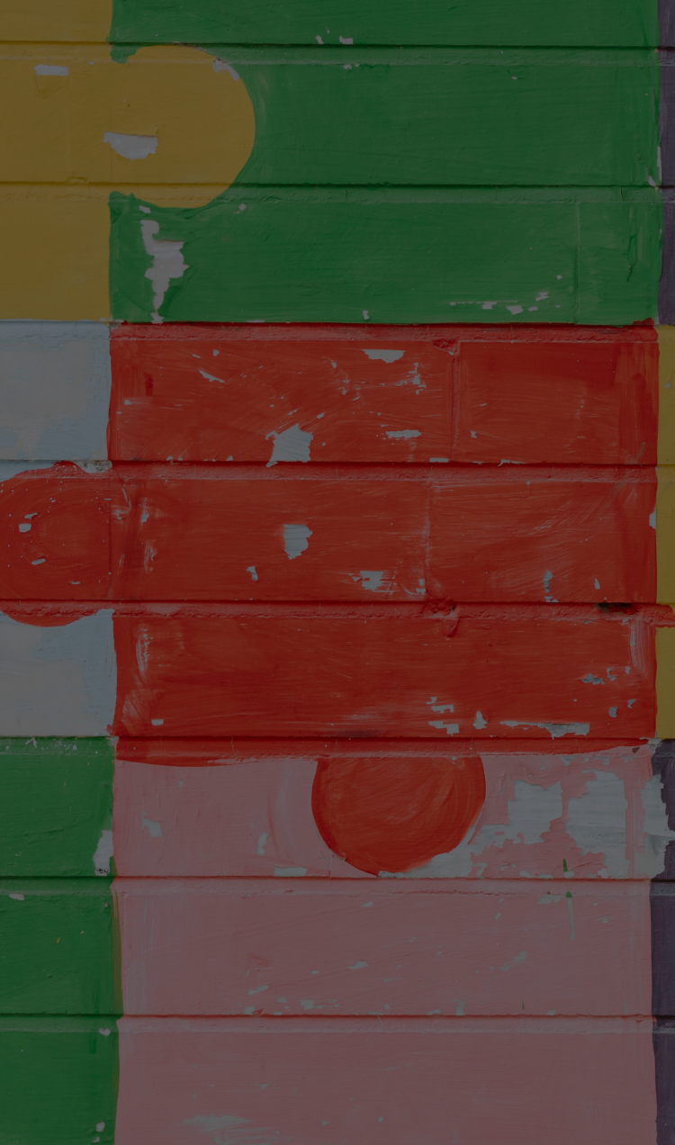 A cinderblock wall painted with a multicolor puzzle pattern.