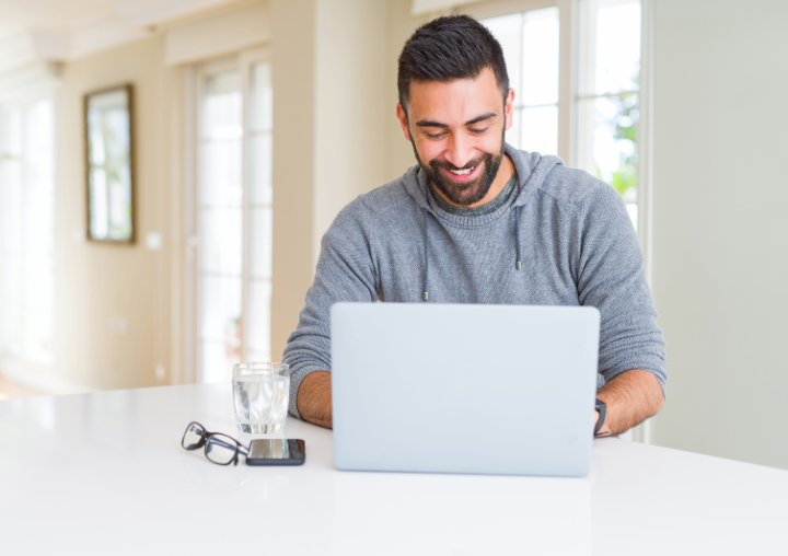 A man engages in an online peer support group from his laptop at home.