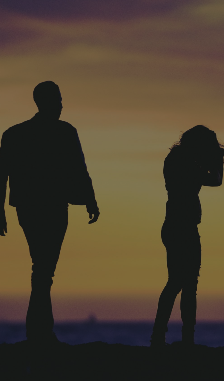 A silhouette of a distant couple on the beach backlit by the sunset.