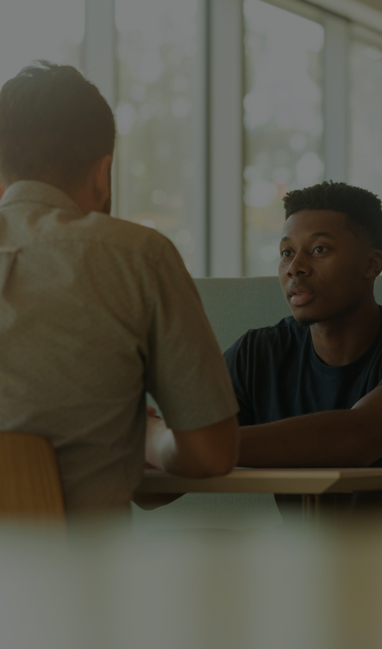 Two men sit together at a table and have a serious conversation.