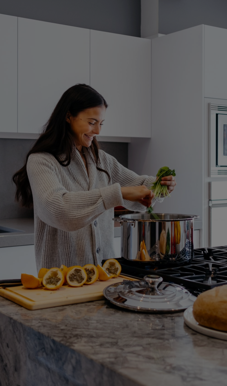 A woman cooks food while prepped fresh ingredients sit on the counter.