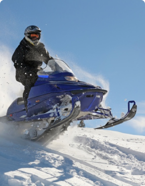 A client snowmobiles over a hill.