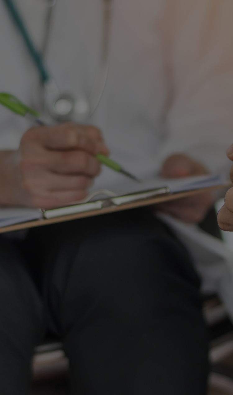 A clinician sitting with a client taking medical notes.