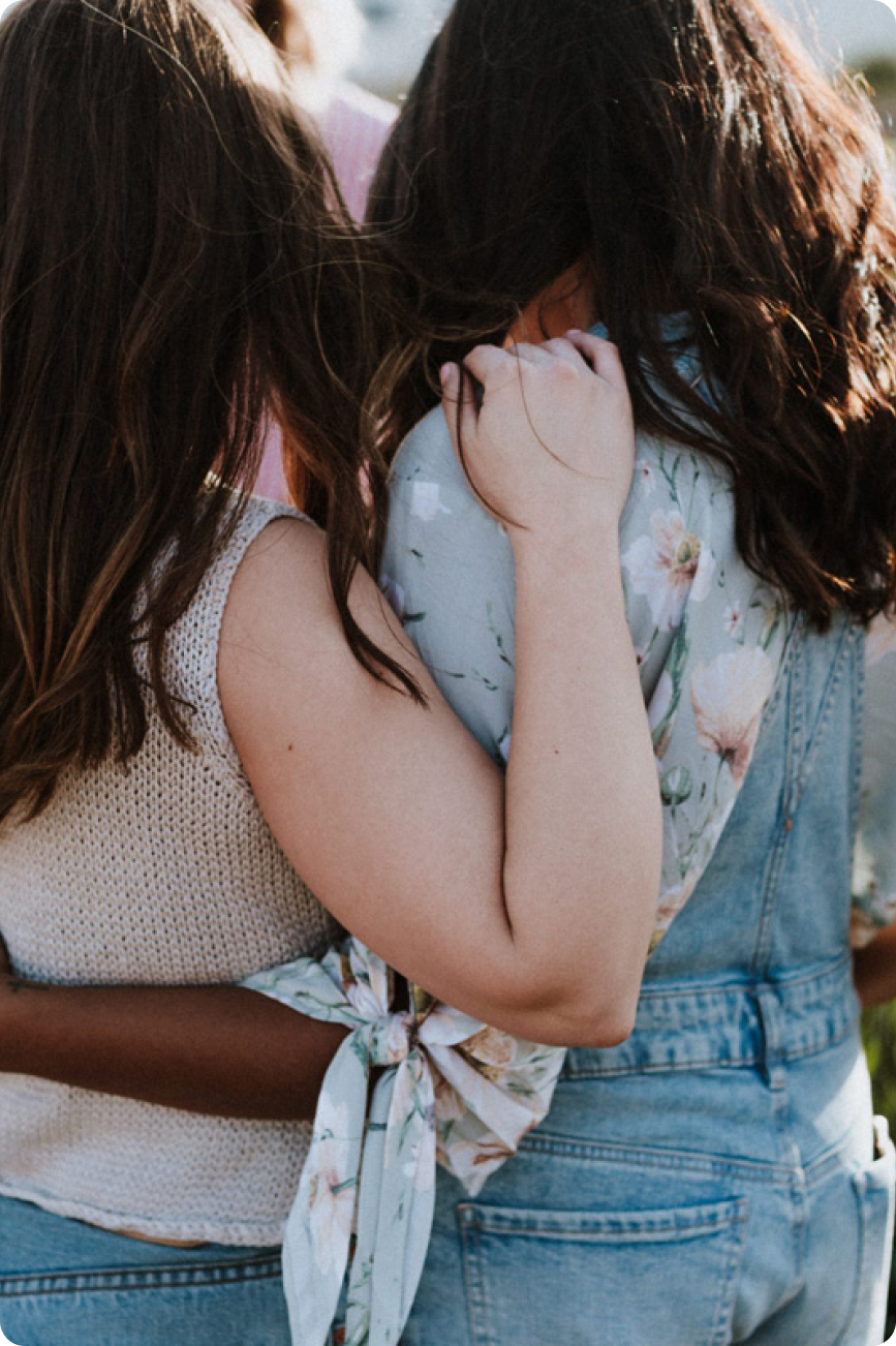 Two women holding each other in a field of flowers.