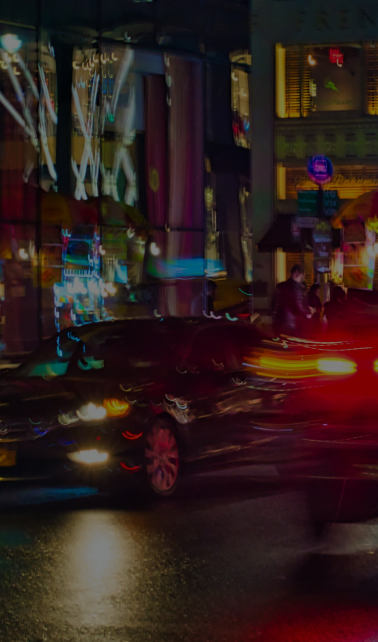 An emergency vehicle moving through nighttime traffic on a New York Street.