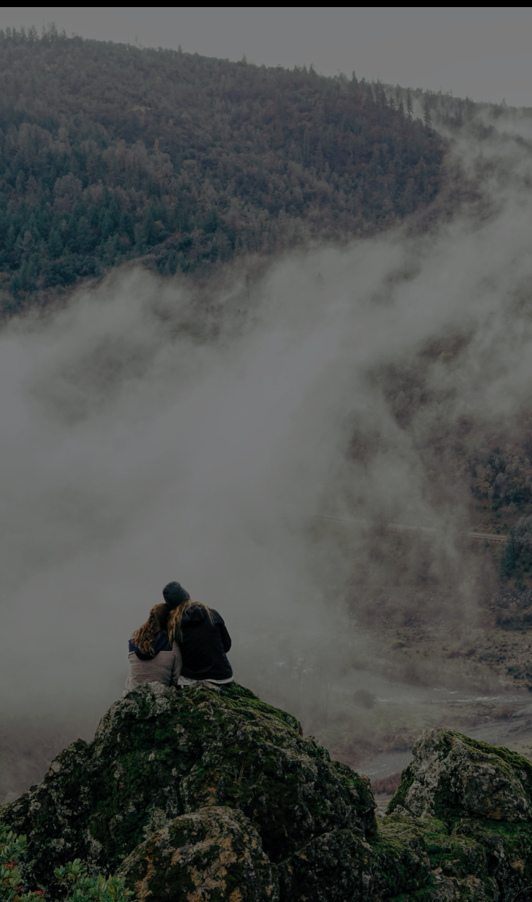 A couple embraces on a misty mountaintop.