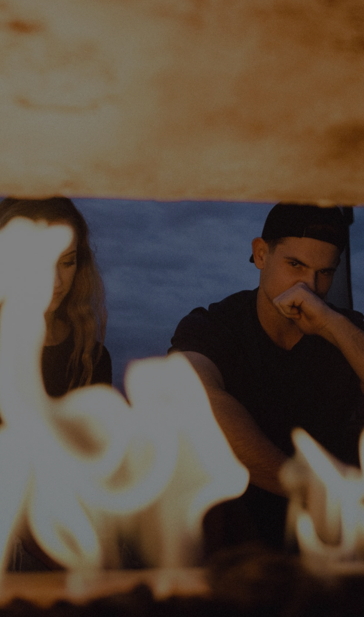 A couple having a disagreement by a fire.